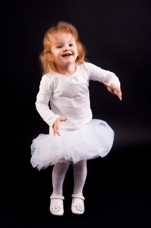 Two years old baby girl wearing white suit at black background の写真素材