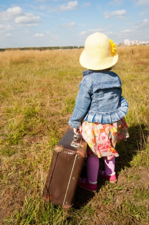 Young beautiful girl with suitcase at country side  Back viewの写真素材