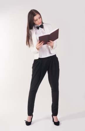 Portrait of pretty student or businesswoman in smart casual reading organizer at white backgroundの写真素材