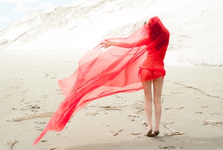 Portrait of a beautiful sexy woman standing at sand backgroundの写真素材