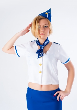 Attractive young stewardess with salute gesture over white backgroundの写真素材