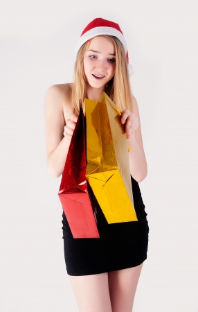 Young attractive woman with christmas hat looking in bag and surprised at white の写真素材