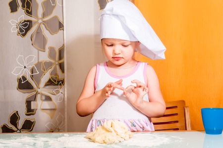 Cute little cook girl molds cookies from doughの写真素材