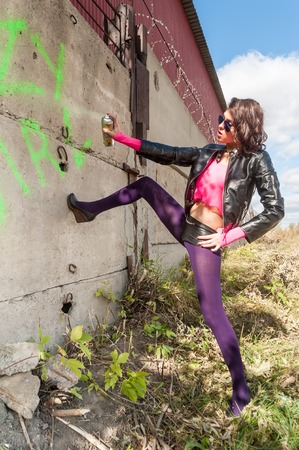 Young beautiful woman in sunglasses with spray paint at wall backgroundの写真素材