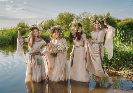 Four attractive women with wreath of flowers enter in lake water  Ivan Kupala Holiday Celebration 