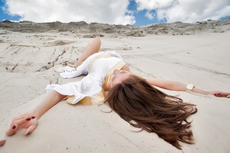 Young pretty sexy woman in greek tunic lies on sand blindlyの写真素材