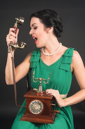 Young pretty woman cries into phone over black の写真素材