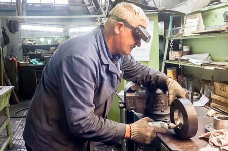 Tyumen, Russia - November 14, 2007: JSC Tyumenskie Motorostroiteli (Plant on production and repair of aviation engines). Mechanic grinds detail on factoryのeditorial素材