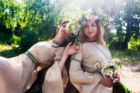 Attractive women in traditional russian clothes relaxes over nature background (Ivan Kupala Holiday Celebration)の写真素材