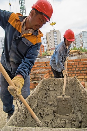 Tyumen, Russia - May 23, 2008: Construction of 18 floor brick residental house at intersection of streets of Gercena and Chelyuskincev. Workers knead solution for bricklayersのeditorial素材