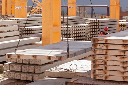 Tyumen, Russia - August 13, 2013: Finished goods warehouse at Concrete Goods Plant No. 5. Worker builder in helmet manages construction processのeditorial素材