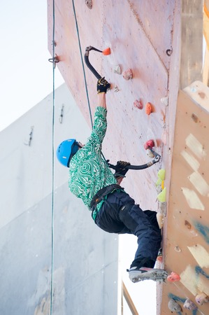 Tyumen, Russia - March 31, 2012: Rock climbing wall of Alkor club. Ice climbing competition. Man climbs upwardのeditorial素材