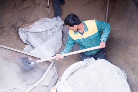 Tyumen, Russia - May 23, 2008: Construction of 18 floor brick residental house at intersection of streets of Gercena and Chelyuskincev. Builder man working with shovel in cement warehouseのeditorial素材