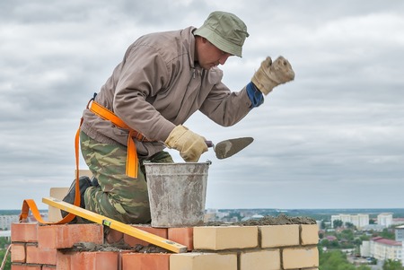 Tyumen, Russia - May 23, 2008: Construction of 18 floor brick residental house at intersection of streets of Gercena and Chelyuskincev. Bricklayer behind work on 15th floor of the buildingのeditorial素材