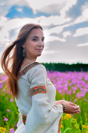 Attractive woman in traditional national dress relaxes with flowersの写真素材