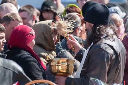 Tyumen, Russia - April 27, 2008: The orthodox priest consecrates believers and Easter cakes with the help an aspergillum. Easterのeditorial素材