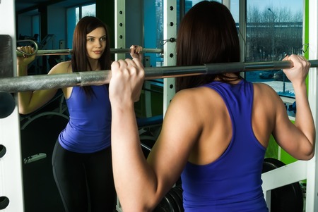 fitness, sport, powerlifting and people concept - sporty woman exercising with barbell in gymの写真素材