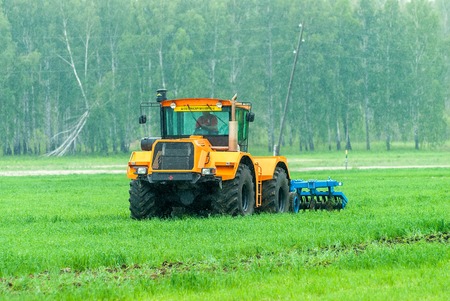 Tyumen, Russia - June 24, 2016: The 5th open championship of Russia on a plowed land. Operator plows the site on Belarus tractor in rainy weatherのeditorial素材
