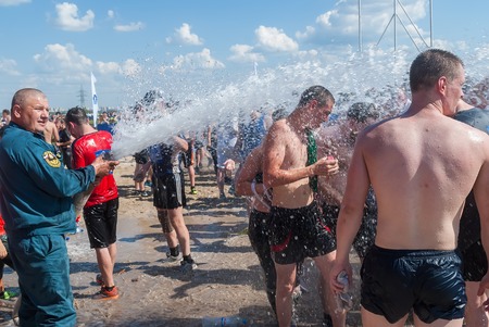 Tyumen, Russia - July 9, 2016: Steel Character extrim race on Voronino Hill. Firefighter pours water from a hose of the wishing athletes after finishingのeditorial素材