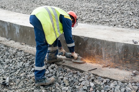 Tobolsk, Russia - July 15. 2016: Sibur company. Construction of plant on processing of hydrocarbonic raw materials. Worker cuts off surplus of fittings on the base under big tankのeditorial素材