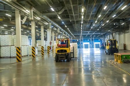 Tobolsk, Russia - July 15. 2016: Sibur company. Central control panel of Tobolsk Polymer plant. Driver on forklift truck loads pallets with finished goods from packaging machine to warehouseのeditorial素材
