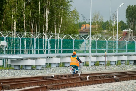 Tobolsk, Russia - July 15. 2016: Sibur company. Woman in working uniform goes by bicycleのeditorial素材