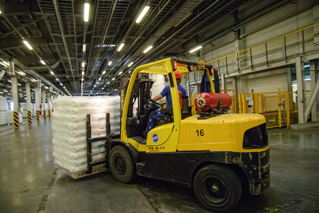 Tobolsk, Russia - July 15. 2016: Sibur company. Central control panel of Tobolsk Polymer plant. Driver on forklift truck loads pallets with finished goods from packaging machine to warehouseのeditorial素材