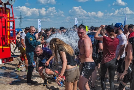 Tyumen, Russia - July 9, 2016: Steel Character extrim race on Voronino Hill. Firefighter pours water from a hose of the wishing athletes after finishingのeditorial素材