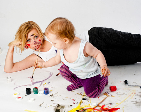 Beautiful young woman with 13 monthes old daughter drawing by paintbrushの写真素材
