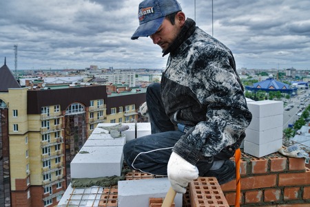Tyumen, Russia - May 23, 2008: Construction of 18 floor brick residental house at intersection of streets of Gercena and Chelyuskincev. Bricklayer behind works on 18th floorのeditorial素材