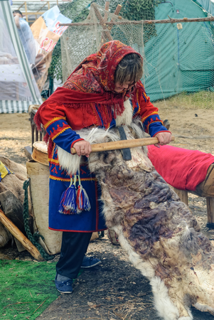 Tyumen, Russia - June 24, 2016: The 5th open championship of Russia on a plowed land. Nenets woman processes cervine skin in cultural center of North people. Nenets - aboriginals of Russian Northのeditorial素材
