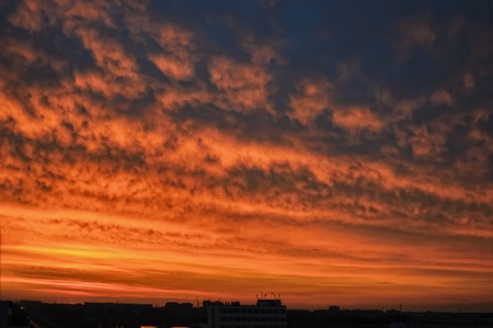 Dramatic sunset and sunrise sky over residential building roofsの写真素材