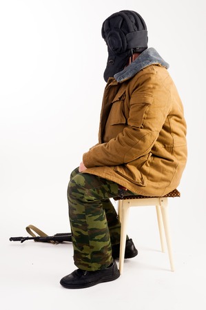 The officer-tankman with the AKM assault rifle sits on a stool. Isolated over white backgroundの写真素材