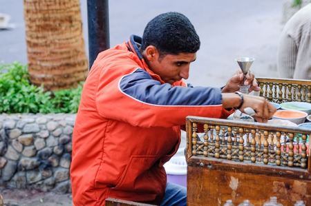 Hurghada, Egypt - November 5, 2006: The man sells spices for a hookah. He prepares mix for sale
