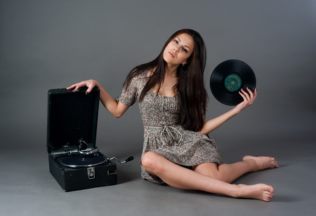 Beautiful woman with gramophone over grey backgroundの写真素材