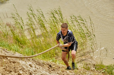 Tyumen, Russia - July 1, 2017: Race of Heroes project on the ground of the highest military and engineering school. Man rises by the steep hill by means of ropeのeditorial素材