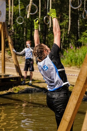 Tyumen, Russia - July 1, 2017: Race of Heroes project on the ground of the highest military and engineering school. The girl climbs on rings over waterのeditorial素材