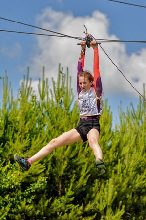 Tyumen, Russia - July 1, 2017: Race of Heroes project on the ground of the highest military and engineering school. Bungee stage. Woman is transported on rope through the riverのeditorial素材
