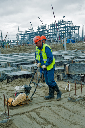Tobolsk, Russia - July 15. 2016: Sibur company. Construction of plant on processing of hydrocarbonic raw materials. Builder worker at sand ground compaction with vibration plate compactor machineのeditorial素材