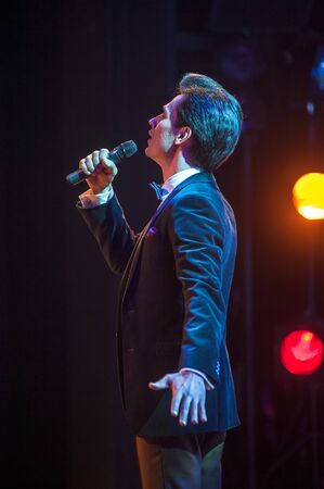 Tyumen, Russia - April 16, 2014: Competition of young performers the Song knows no limit in dramatic theater. Young man in suit singing over the microphoneのeditorial素材
