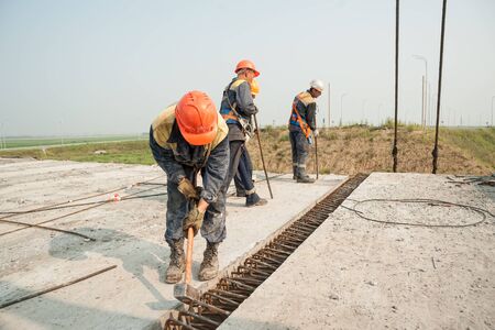 Tyumen, Russia - July 31, 2013: JSC Mostostroy-11. Manual workers mount span of bridge. Bridge construction for outcome of the Tobolsk path and Bypass road round Tyumen.のeditorial素材