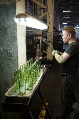 Bogandinskiy, Russia - April 20, 2018: Stekloteh factory on bottles production. Worker controls quality of bottle, Tyumen regionのeditorial素材