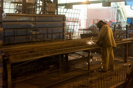 Tyumen, Russia - August 13, 2013: Block making department at construction material factory ZHBI-5. Welder with protective mask welding metal and sparksのeditorial素材