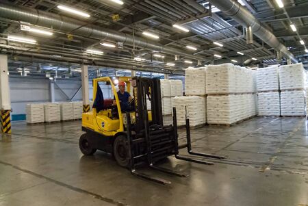 Tobolsk, Russia - July 15. 2016: Sibur company. Polymer plant. Driver on forklift truck loads pallets with finished goods from packaging machine to warehouseのeditorial素材