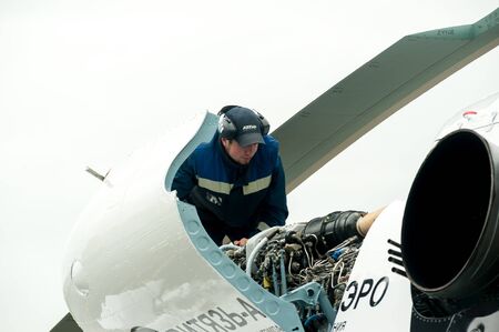 Tyumen, Russia - June 19, 2019: Aircraft repair helicopter UTair Engineering plant. Male mechanic in uniform examining helicopter. Pre flight inspection at the airportのeditorial素材