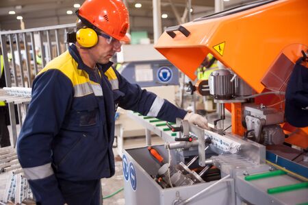 Tyumen, Russia - November 30, 2017: Workshop of Mostootryad-36 Factory. Plastic window and door manufacturing. Worker cutting PVC profileのeditorial素材