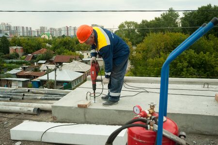 Tyumen, Russia - September 4, 2019: JSC Mostostroy-11. Bridge reconstruction on Chelyuskincev street. Manual worker drilling concreteのeditorial素材