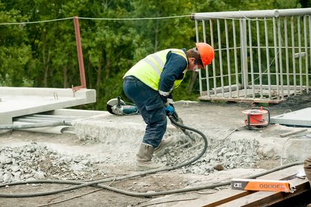 Tyumen, Russia - September 4, 2019: JSC Mostostroy-11. Bridge reconstruction on Chelyuskincev street. Manual worker with jackhammer to break up a reinforced concrete pavementのeditorial素材