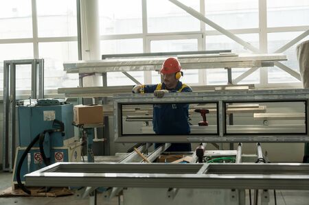 Tyumen, Russia - September 4, 2019: Workshop of Mostootryad-36 Factory. Plastic window and door manufacture workshop. Worker doing installationのeditorial素材