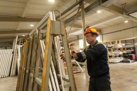 Tyumen, Russia - September 4, 2019: Workshop of Mostootryad-36 Factory. Plastic window and door manufacture workshop. Worker doing installationのeditorial素材